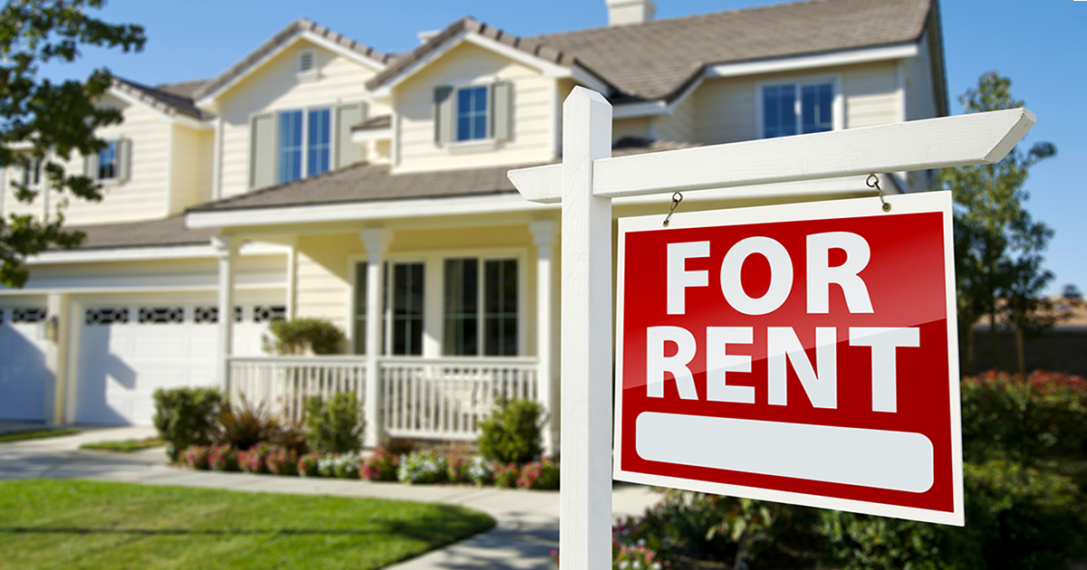 For rent sign hanging in front of white two-story home with front porch