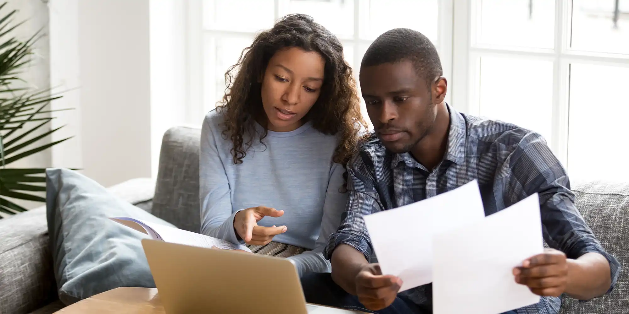 young african american couple reviewing documents on their couch in a bright modern room