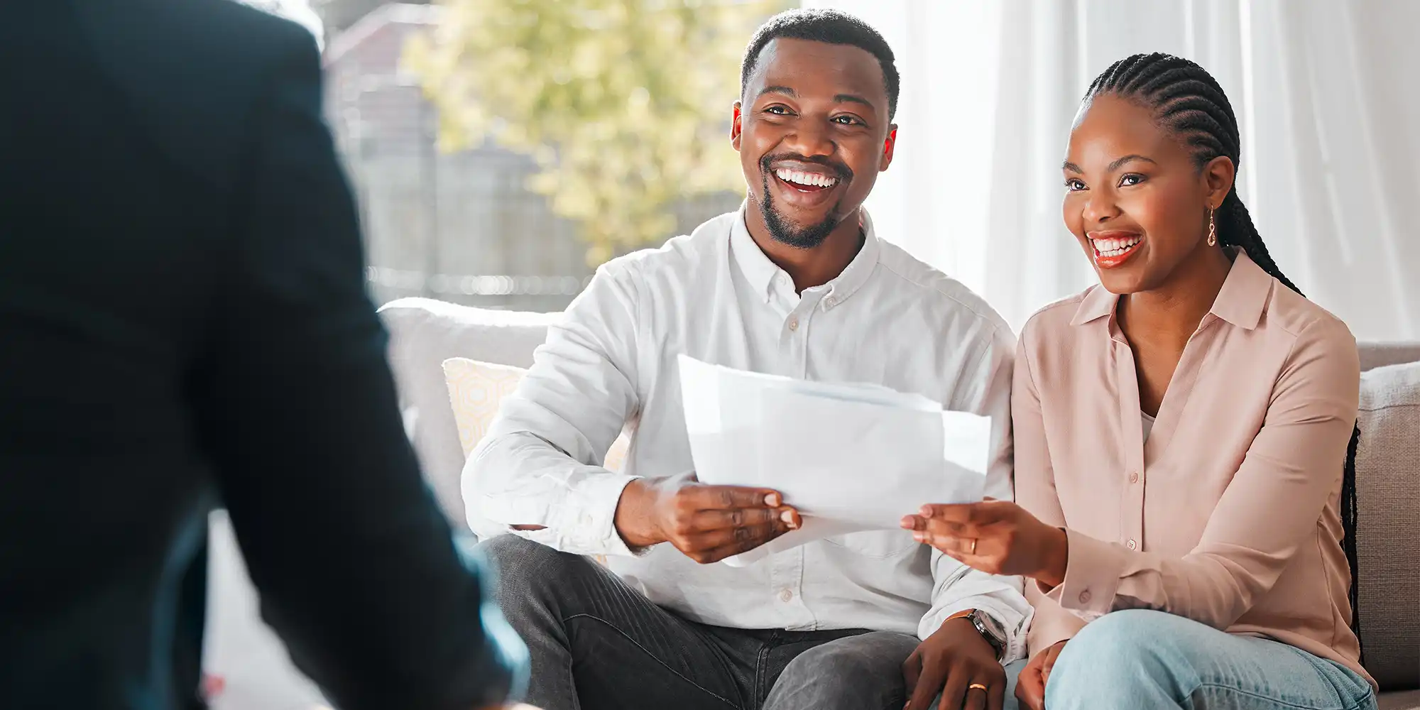 african american heterosexual couple in their 30s meeting with person in suit while seated on a couch