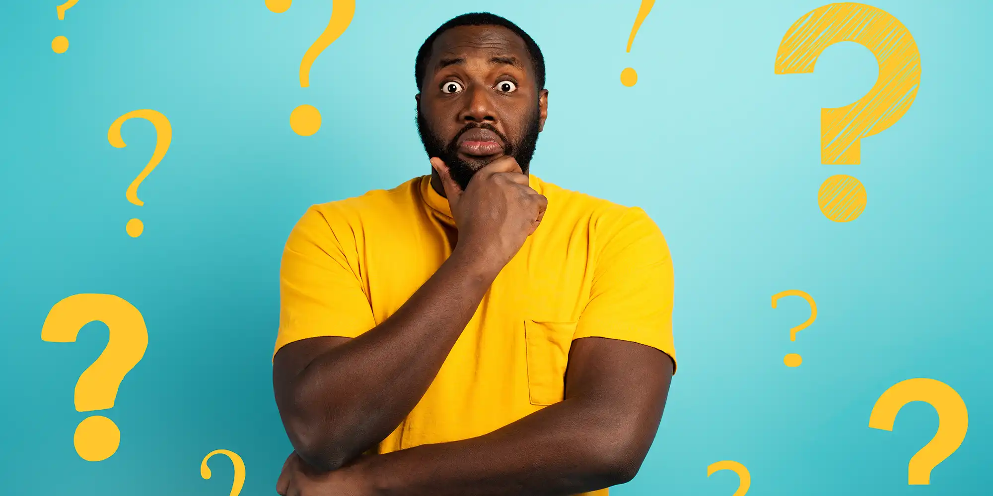 middle aged african american man wearing bright yellow shirt surrounded by yellow question marks in front of blue wall