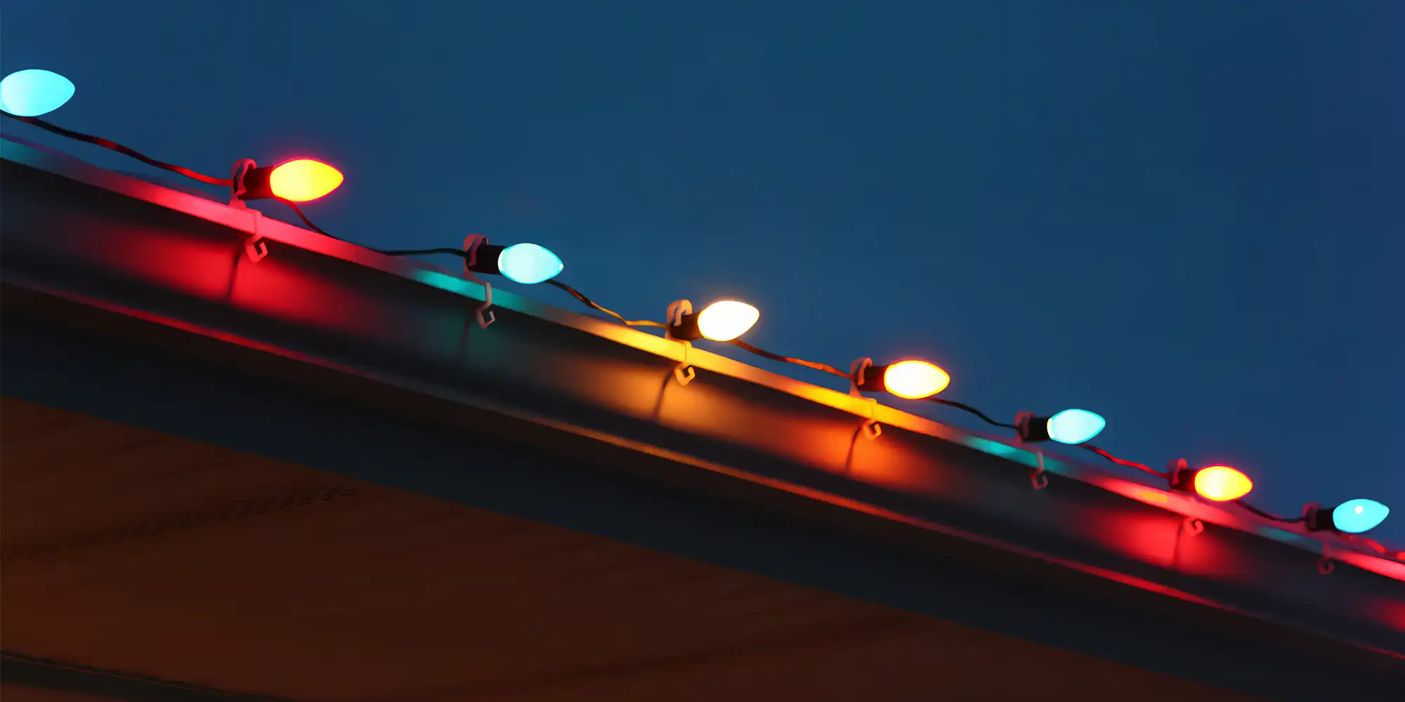 zoomed in view of colorful christmas lights lining the edge of a roof