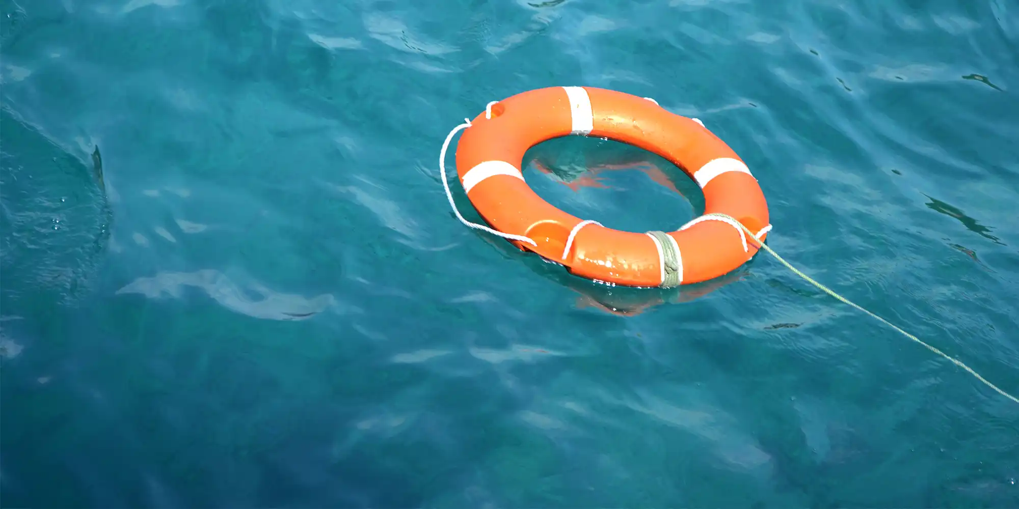 orange life preserver floating on teal colored water