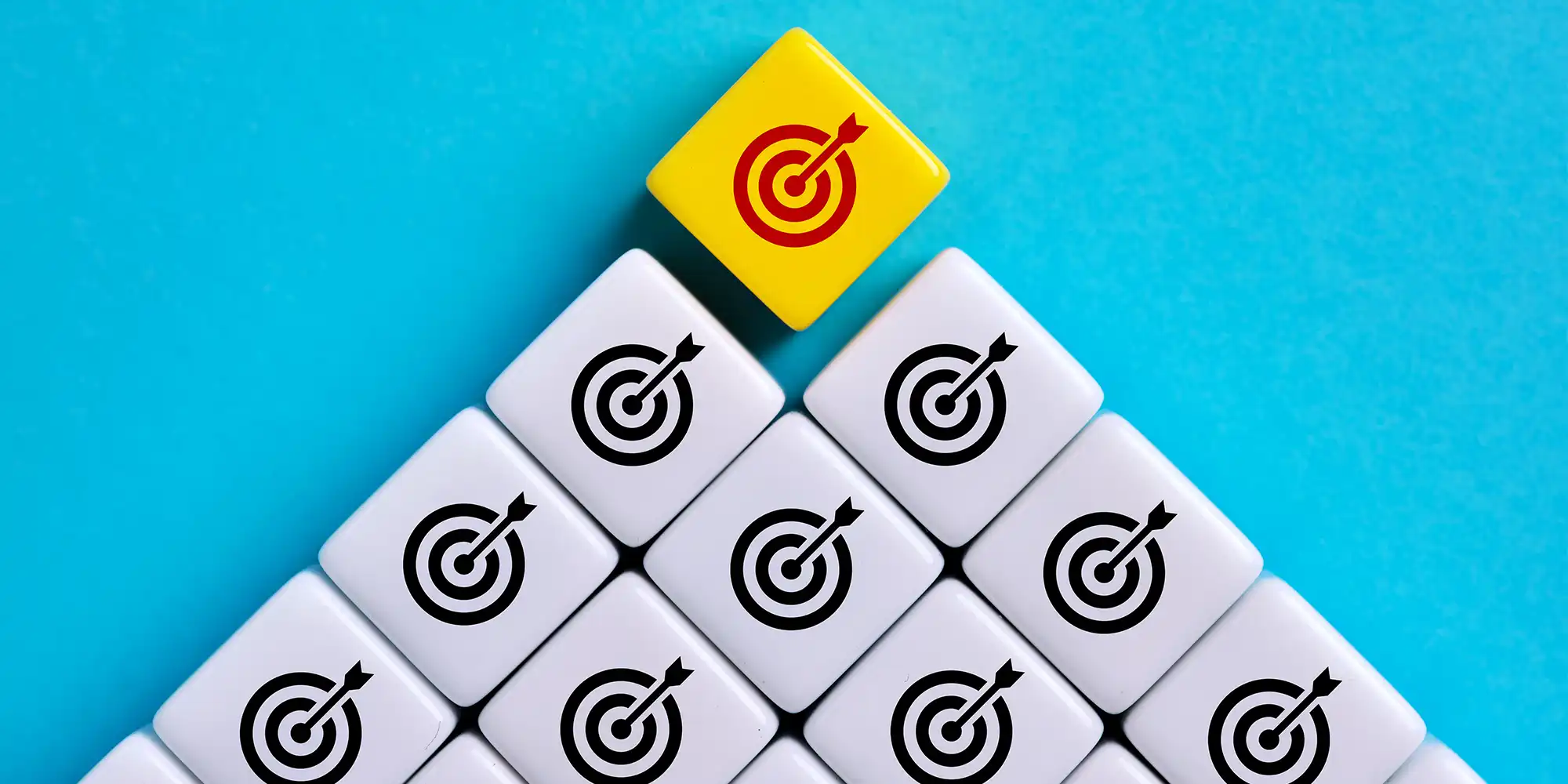 pyramid of square tiles showing bullseye icon on each. All are black and white except the top one is yellow with a red icon.