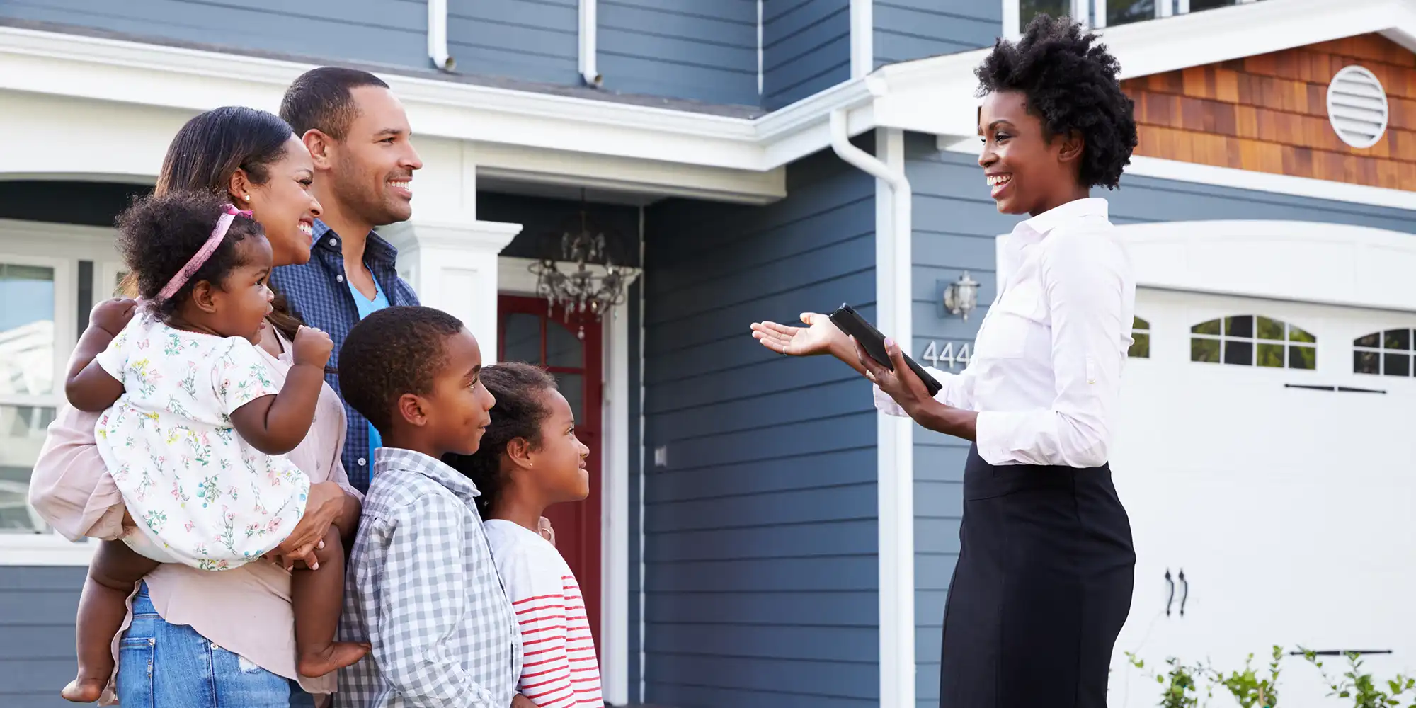 african american family with three young children looking at two story home with blue siding with young african american realtor