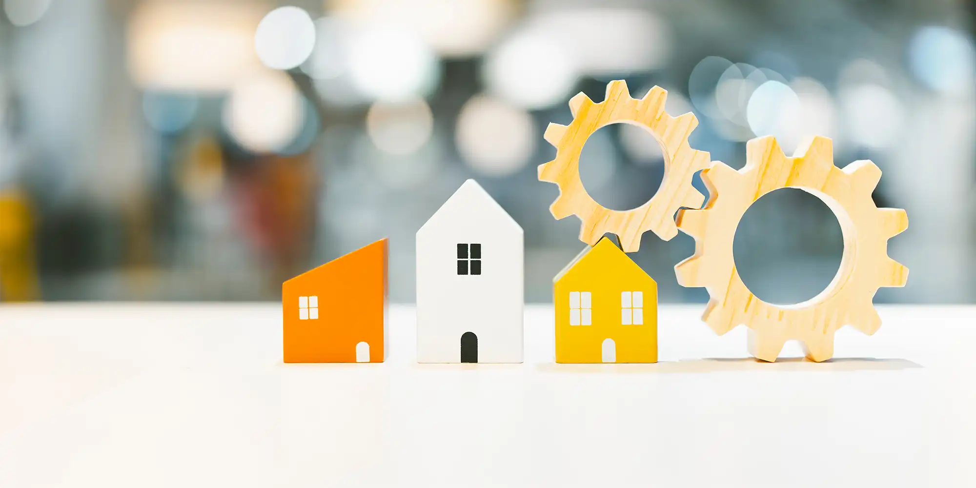 orange white and yellow wooden block house shapes next to two wooden gear shapes