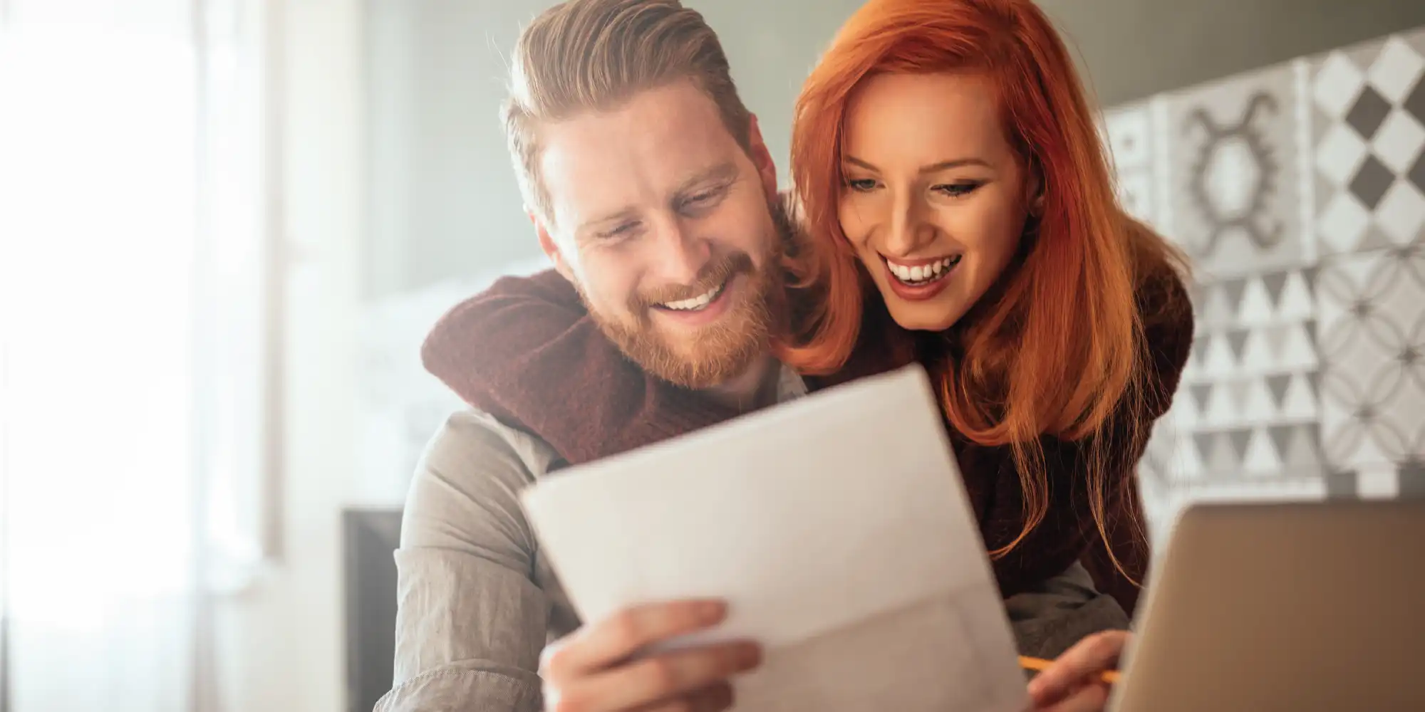 caucasian man and woman looking at their mortgage statement smiling