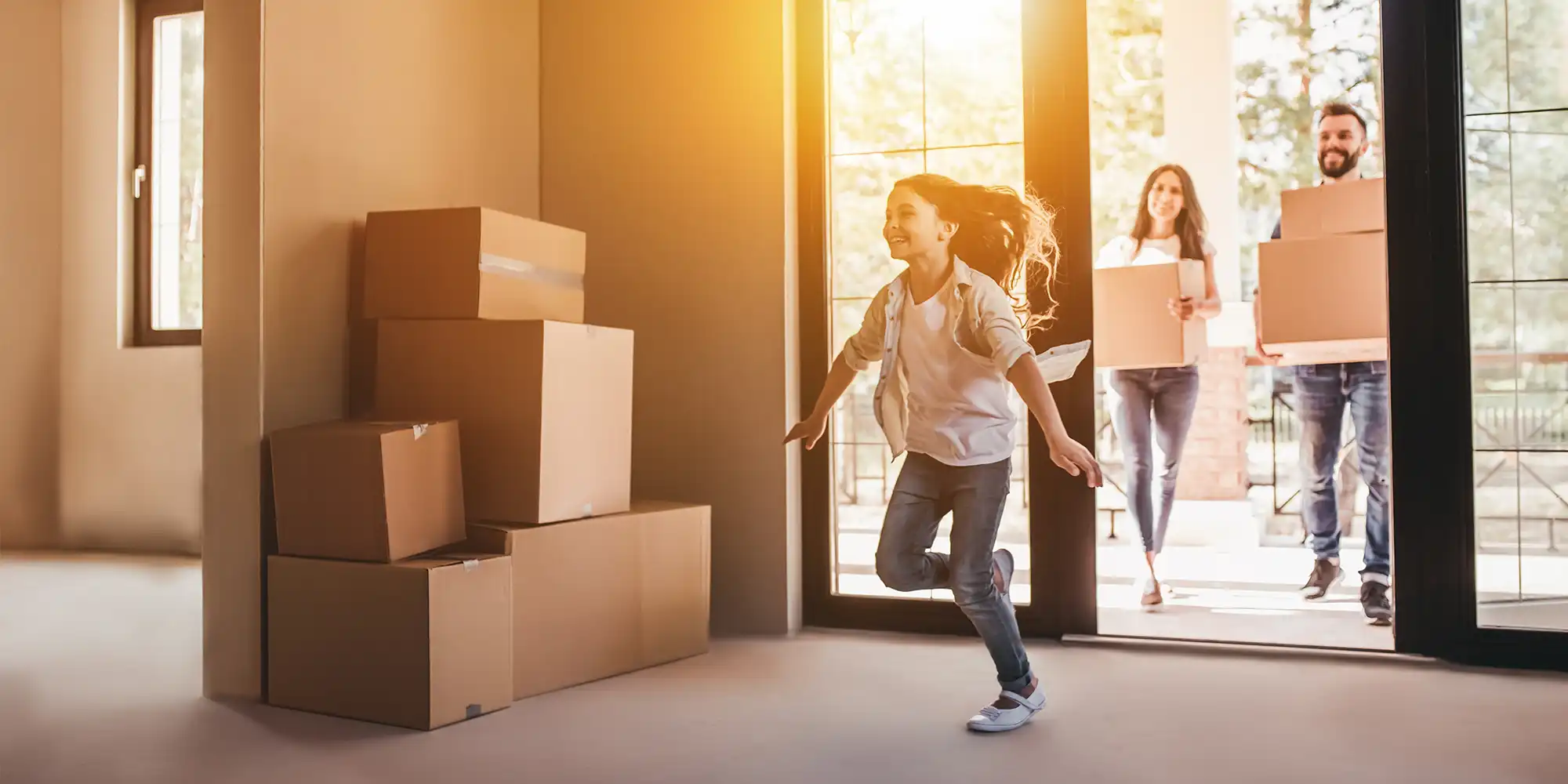 parents and teen daughter happily moving into new home with sunshine shining through front door
