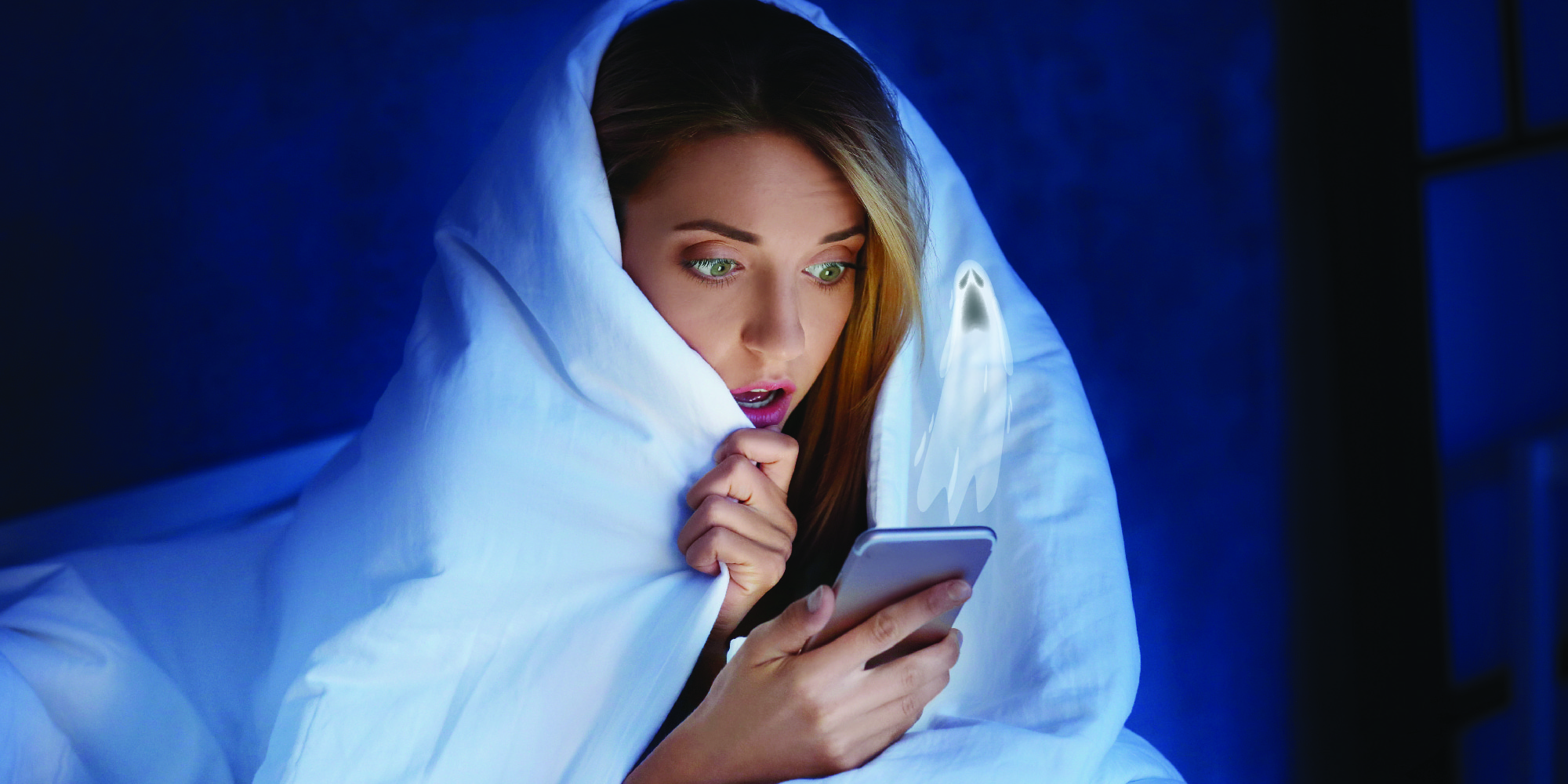 white woman with blond hair sitting wrapped in white blanket looking at phone with worried expression