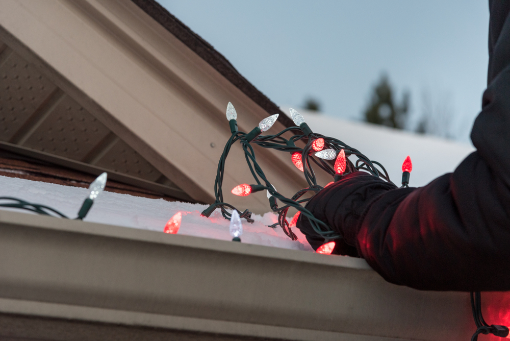 man hangs holiday lights  at home