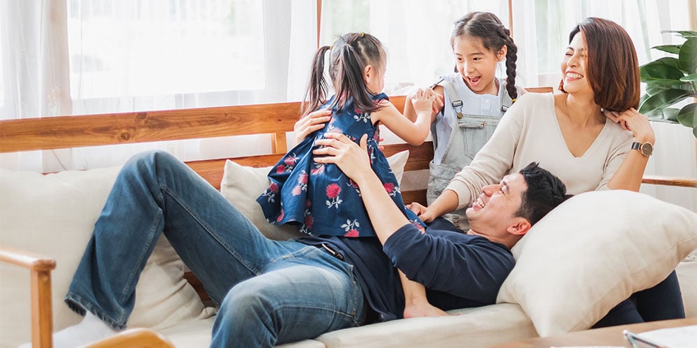 young-multiracial-family-playing-on-couch-together